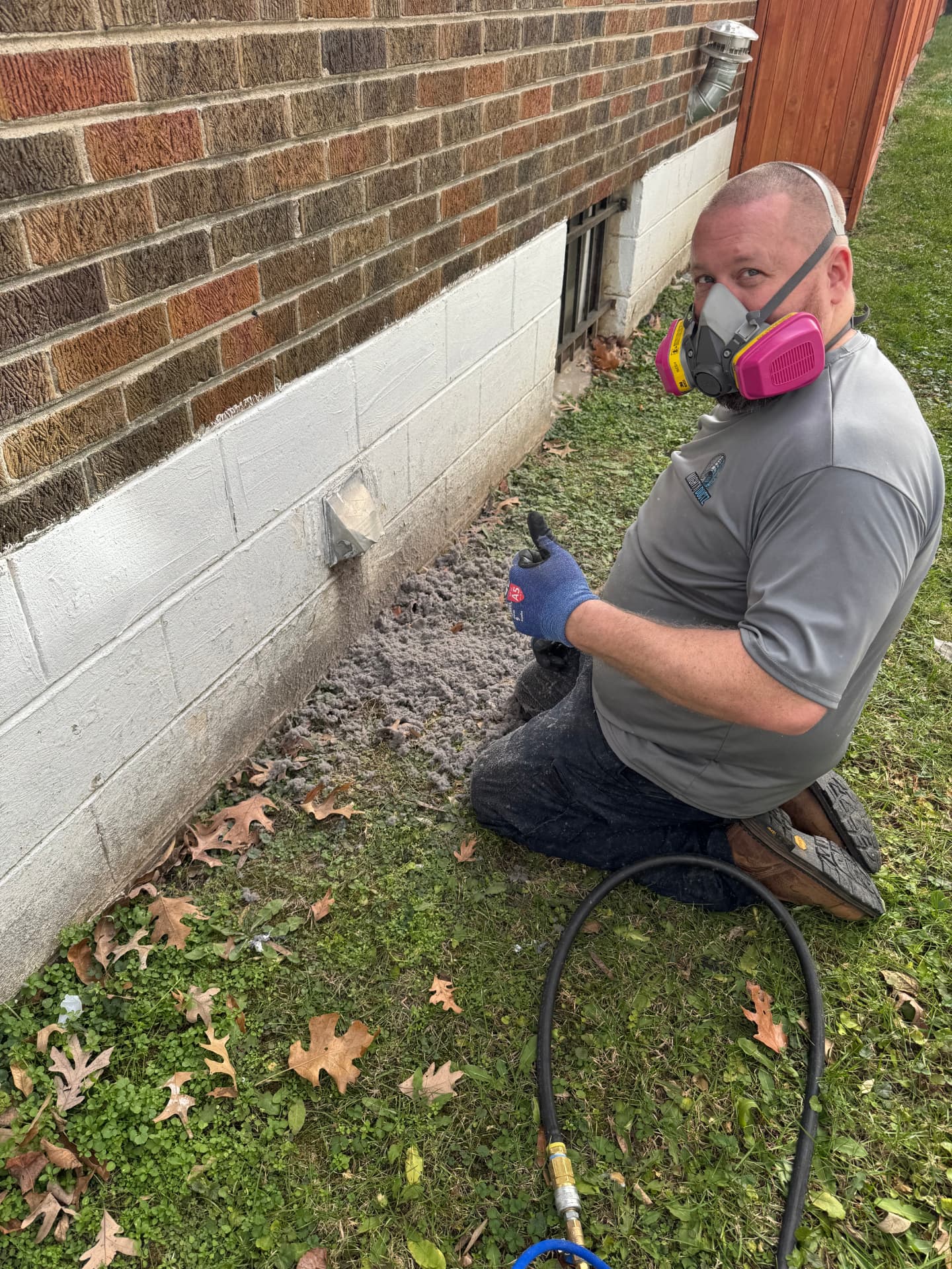 Technician cleaning a dryer vent exhaust from the outside of a home, removing built-up lint and debris
